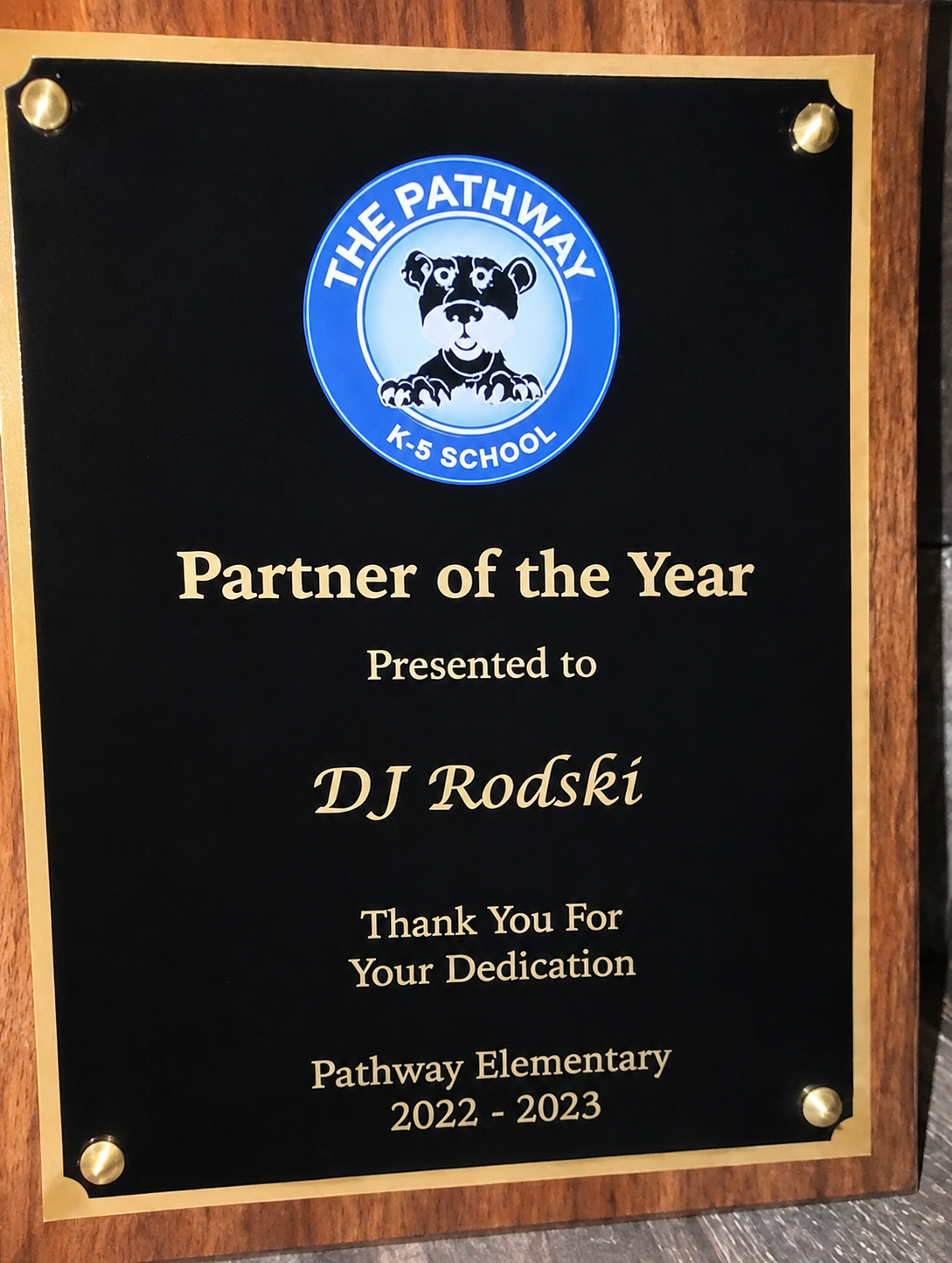 A wooden plaque naming DJ Rodski Partner of the Year at Pathway Elementary for 2022 to 2023